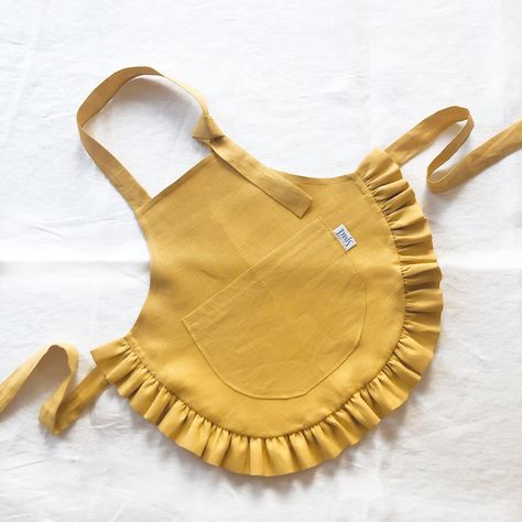 "Linen kids apron with ruffle. Ideal for cooking, gardening, painting and more. Perfect as a gift. Details: - one pocket - easy adjustable with ties Made of: - 100% European linen fabric Oeko-Tex certified linen Color: - Mustard - more colors will be available soon Sizes: - 2-4 years: 48x42 cm / 18.9x16.5\" - ties length 50 cm / 19.7\" - 4-7 years: 55x48 cm / 21.6x18.9\" - ties length 50 cm / 19.7\" - 7-10 years: 62x54 cm / 24.4x21.3\" - ties length 60 cm / 23.6\" Care instruction: - machine wash, 30C / 86F - wash separately or with similar colors - do not bleach - tumble dry on low heat - Iron on low heat (if needed) --- 📩 If you have any questions about our products, please don't hesitate to contact us." Gardening Painting, Baby Apron, Baby Bumper, Ruffle Apron, Toddler Apron, Linen Pinafore, Aprons Patterns, Bib Apron, Linen Color