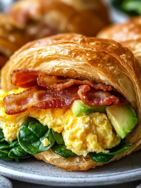 Imagine starting your day with a decadent breakfast that feels like a warm hug – that's exactly what Croissant Breakfast Bliss offers! Layers of fluffy scrambled eggs mixed with sharp cheddar, crispy bacon, sautéed spinach, and creamy avocado, all housed in a buttery croissant. This dish isn't just a morning meal; it's an experience of textures and flavors that will elevate any breakfast ta... Scrambled Egg Croissant, Fancy Breakfast Sandwich, Egg Croissant Breakfast, Crissonts Sandwich Ideas, Stuffed Croissants Breakfast, Crossiant Breakfast Sandwich, Cresants Recipes Breakfast, Meals That Are A Warm Hug, Breakfast Croissant Ideas