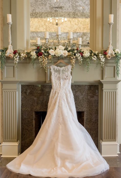 Wedding dress hanging on fireplace mantel Wedding Flowers Over Fireplace, Christmas Wedding Mantle Decor, Fireplace Mantle Flowers Wedding, Fireplace Mantle Decor Wedding, Wedding Mantle Decorations, Fireplace Wedding Flowers, Fireplace Mantle Wedding Decor, Wedding Fireplace Flowers, Mantle Wedding Decor