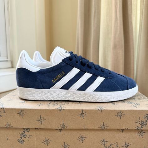 New Adidas Gazelle Sneakers Navy White Gold New Without Box Men's Size 5.5 / Women's Size 6.5 Color: Navy Blue White Gold Metallic Collegiate Navy Cloud White Lace-Up A Pair Of Adidas Gazelles And Feel The Vintage Vibes. Bringing Back The 1991 Form, This Reissue Offers The Signature Suede Upper In Versatile Colors. Contrasting Details Pop Against The Sleek Silhouette And Tie-In The Rubber Sole For A Cohesive Effortless Style. Whatever The Occasion, These Shoes Are Ready To Make A Bold Statement. Navy Blue Adidas Gazelle, Addias Gazzels, Bts Shoes, Addias Shoes, Adidas Gazelle Blue, Adidas Gazelle Outfit, Adidas Gazelle Women, Random Wishlist, Adidas Gazelles