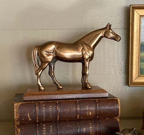 Our beautiful antiqued brass horse is mounted to a wooden stand and is a perfect piece for the equestrian or horse lover. It is rather small, only 7" long and 5-1/2" tall, so it would be great as part of a shelf or tabletop vignette, and would also be a wonderful gift. And, quite honestly, the pictures do not do it justice- it's a really great, versatile piece. - 7" long by 5.5" tall by 3" wide - Solid brass horse mounted to wooden stand - Antiqued brass for a vintage look - Antique reproduction Antique Horse Decor, Equestrian Decor Interior Design, Equestrian Interior Design, Vintage Hunting Decor, Equestrian Chic Decor, Equestrian Style Decor, Horse Decorations, Vintage Brass Decor, Equestrian Chic