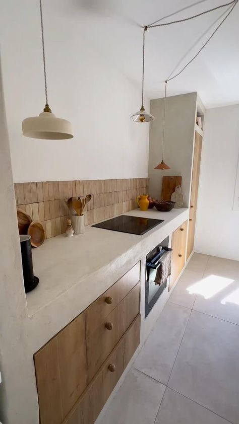 This Mediterranean-inspired kitchen blends rustic and contemporary elements with stucco countertops, wood cabinetry, and rattan pendant lights. An integrated bench with plush cushions adds comfort. Earthy tones and minimalist decor enhance the coastal vibe. SHOP similar products tagged. #MediterraneanKitchen #RusticCharm #StuccoCountertops #WoodCabinetry #RattanPendants #BenchSeating #MinimalistDecor #EarthyTones #CoastalVibe #HomeDecor #KitchenDesign #Benchseatingc#rattan #rattandecor Modern Mediterranean Kitchen, Mediterranean Style Kitchen, Cement Kitchen, Resin Kitchen, Mediterranean Kitchen Design, Contemporary Mediterranean, Inspiration Deco, Cottage Decor Living Room, Mediterranean Interior