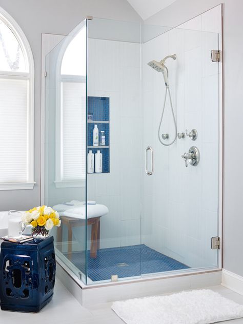 White and blue bathroom features oval freestanding bathtub paired with cobalt blue stool placed under arched window beside a seamless glass shower filled with white tiles framing a blue tiled niche over teak shower bench atop blue tiled shower floor. Blue White Bathrooms, Blue And White Bathroom, Small Bathroom With Shower, Small Showers, Master Bath Ideas, Diy Vanity, Vinyl Decor, Bathroom Remodel Shower, Master Bath Remodel