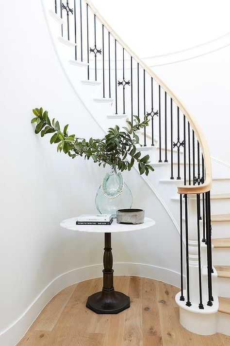 Lovely curved wrought iron staircase and nook furnished with a small French table designed with a round marble top and a recycled glass vase. French Staircase, Round Foyer, Salt Interiors, Round Entry Table, Stair Nook, Round Stairs, Pure Salt Interiors, Wrought Iron Staircase, Iron Staircase