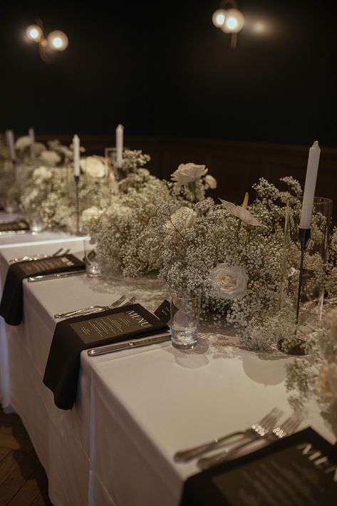 To bring their modern Art Deco reception to life, the bride and groom chose timeless black and white elements, as well as clear architectural details including their seating chart with white printed lettering in a variety of contemporary fonts. Black and white linens were adorned with trendy baby's breath centerpieces accented by full white roses. #weddingdecor #weddingideas #babysbreath December Wedding Black And White, Trendy Wedding Centerpieces, Black And White Wedding Dinner, Black White And Beige Wedding Decor, White Wedding Black Accents, Black And White Bride And Groom, Black Tie Wedding Reception Centerpieces, Wedding Table Decorations Black And White, No Flower Centerpieces Wedding