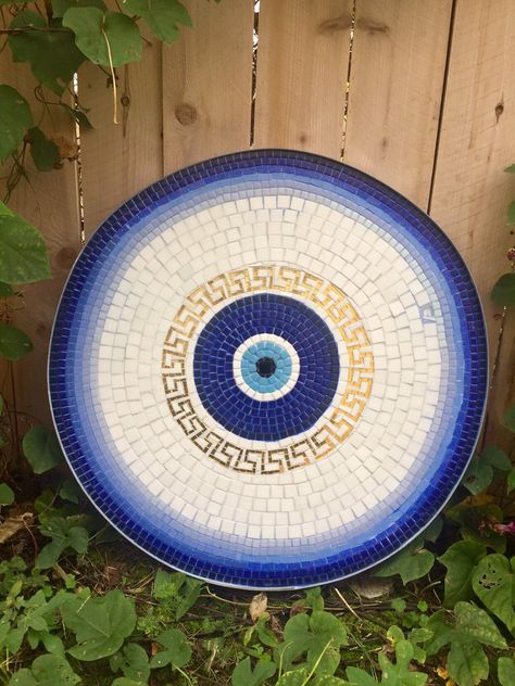 These mosaic bistro tables are handmade with cut glass using my unique pattern of Greek key and lucky eye on background of blue and white. These handmade table tops can be used as side tables, coffee tables, patio tables or can fit onto any other other table you have and they range in size between 22 and 26 inches. The outer rim is a wine barrel hoop, Inset with a custom cut waterproof cement board. They're weatherproof enough to go outside and stain proof and they make great gifts or additions Table Top Mosaic Ideas, Mosaic Top Table, Mosaic Table Top Designs Patterns, Mosaic Round Table Top, Mosaic Bistro Table, Greek Decor Outdoor, Mosaic Table Top Diy Outdoor, Mosaic Stump, Round Table Painting Ideas