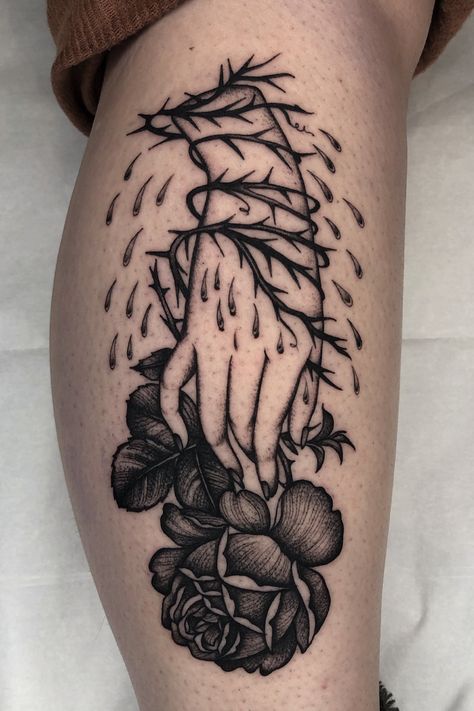 A person shows their calf tattoo. It is a rose tattoo and thorns tattoo with a hand grasping a rose, thorns surrounding the hand, and drops of blood dripping around the hand. It is done in a Blackwork Illustrative style. Thorns Around Knee Tattoo, Thorns Hand Tattoo, Traditional Thorn Tattoo, Rose And Thorns Tattoo, Spray Painted Flowers, Rose With Thorns Tattoo, Blackwork Rose Tattoo, Tattoos Hands, Hands Grasping