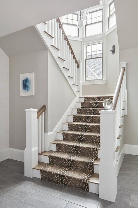 A white staircase post is fitted with a crystal ball fixed in front of a brown stained wood handrail  accenting white wooden spindles, while an antelope print runner covers brown stained wood treads. Staircases With Runners, Staircase Post, Entry Remodel, Antelope Print, Staircase Spindles, Black Railing, Rustic Staircase, Split Entry, Open Concept Great Room