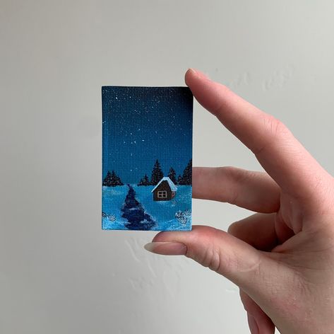 Original mini landscape painting of a snowy winter cabin, featuring a cold river and distant trees. This is a magnetic canvas and would look great displayed in an office or on the fridge! This original painting is sealed with an insulation coat and a satin varnish, giving the piece a slightly glossy appearance. The varnish increases the longevity of the piece and protects it from UV light, dust, and grease. Moisture could still affect the paint, and paintings will be carefully wrapped to avoid a Mini Canvas Christmas Paintings, Snowy Painting, Mini Landscape, Winter Cabin, Blue Winter, Snowy Winter, Small Canvas Art, Simple Acrylic Paintings, Blue Painting