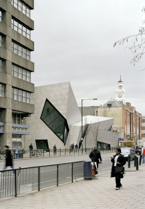 The 10,000 sq. ft. Graduate Student Centre for the London Metropolitan University is an addition to the bustling block on London’s Holloway Road. Composed of three intersecting volumes, clad with embossed stainless steel panels for a shining and ever-changing surface, the Graduate Center houses a lecture theater, seminar rooms, staff offices and a café for the university’s graduate students. The interiors are filled with natural light by way of large windows of geometrical cuts and slashes. T... Deconstructivism Architecture, Libeskind Architecture, University Accommodation, London Metropolitan University, London Accommodation, Study In London, Lecture Theatre, Deconstructivism, Daniel Libeskind