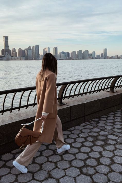 New york city based fashion influencer Lauren Lora wearing a neutral monochrome outfit. She’s wearing a camel wool coat, beige wide leg pants, white sneakers and a brown dior saddle bag. Brown Saddle Bag Dior, Brown Saddle Bag Outfit, Dior Saddle Brown, White Dior Saddle Bag Outfit, Brown Bag Outfit, Edge Outfits, Dior Saddle Bag Outfit, Taupe Outfit, Outfit Cold Weather