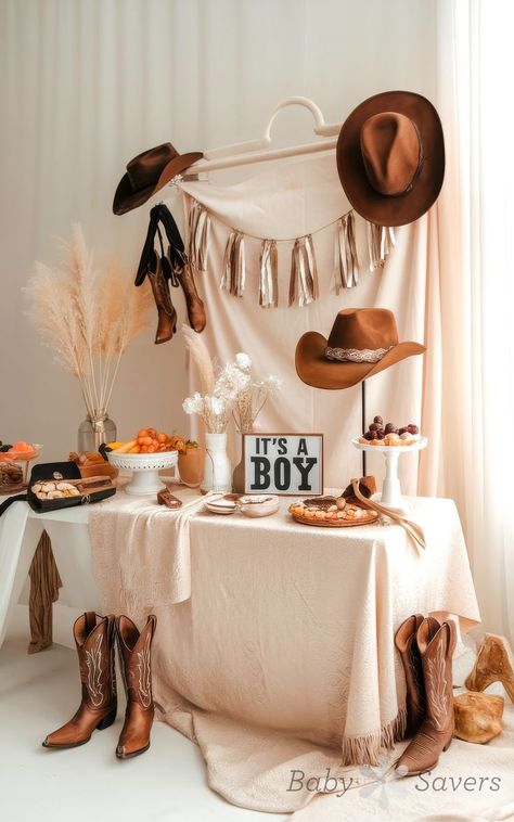 Explore charming baby shower ideas with a western theme, featuring cowboy hats, boots, and delightful decor. A cheerful "It's a Boy" sign adorns a table overflowing with desserts and fruits. Neutral tones and pampas grass beautifully enhance the rustic ambiance. Cowboy Baby Shower Food Ideas, Baby Shower Ideas Western Theme, Cowboy Shower Ideas, A Cowboy Is On The Way, Boy Western Baby Shower Ideas, Little Boy Baby Shower Themes, Horse Theme Baby Shower Ideas, Vintage Cowboy Baby Shower Ideas, Rustic Baby Shower Ideas For Boys