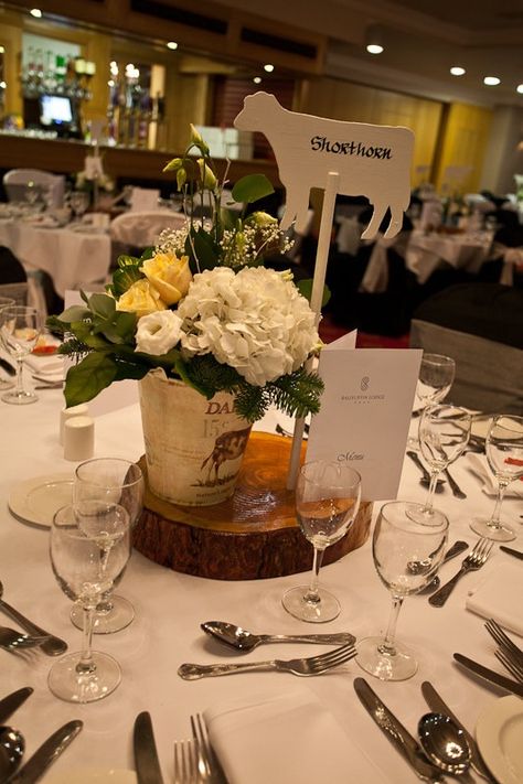 Farm wedding centrepiece. Tree slice, wooden cow with table name written on in calligraphy, milk bucket filled with flowers. Farm Animal Wedding, Cow Table Centerpieces, Farm Wedding Centerpieces, Farm Wedding Favors, Plaas Troue, Dairy Farm Wedding, Cow Wedding, Tractor Wedding, Farmer Wedding