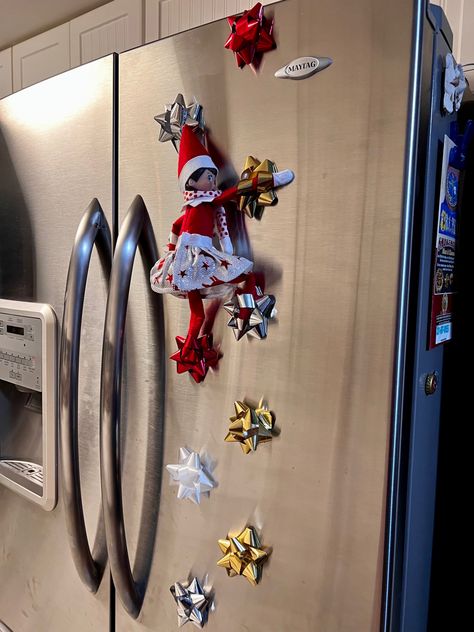 An easy idea with sticky bows and putting the elf in yhe shelf through one of the loops. You could put these on any walls or the refrigerator and make the elf look as if she is climbing! We love our christmas elf on shelf Elf On The Shelf Hanging From Ceiling, Elf On The Shelf Bow Ideas, Elf Climbing On Bows, Elf Look, Elf On Shelf Funny, Elf On Shelf Printables, Elf 2023, Elf Idea, Elf On Shelf