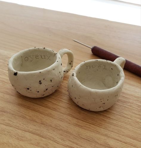 Organic and rustic style mugs - for decoration only, not safe for use! These are a bit harder than the clay candle holders I made previously. Finished mug! Setup: always have a cup of water and extra plastic wrap to keep clay pieces that you aren't working with moist.Shape clay into a ball by rolling it between your palms. Cut the ball of clay in half with your sculpting tool. Put half under plastic wrap to keep it from hardening Hollow out the sphere The mouth is pretty wide… Clay Cup Holder, Air Dry Clay Mugs, Air Hardening Clay Ideas, Cup With Clay, Air Dry Clay Cup, Air Dry Clay Mug, Self Hardening Clay Ideas, Mugs Clay, Handbuilding Pottery