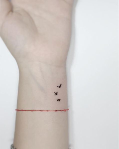 Minimalistic style flying birds tattooed on the wrist. Three Flying Birds Tattoo, Bird With Halo Tattoo, Swallow Flower Tattoo, Dainty Hummingbird Tattoos For Women, Fine Line Bird Tattoos For Women, Wrist Wing Tattoo, Birds Minimalist Tattoo, Birds Tattoo Wrist, Small Birds Tattoo