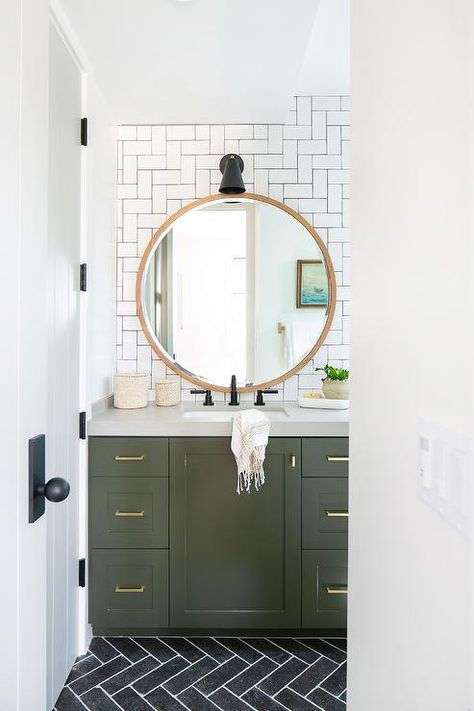 A round blond wood mirror hangs from a wall covered in white subway backsplash tiles arranged in a geometric pattern and contrasted with black grout. Olive Green Bathrooms, Powder Room Design Ideas, Green Bathroom Vanity, Green Vanity, Powder Room Decor, Herringbone Backsplash, Cottage Bathroom, Powder Room Design, Powder Room Small