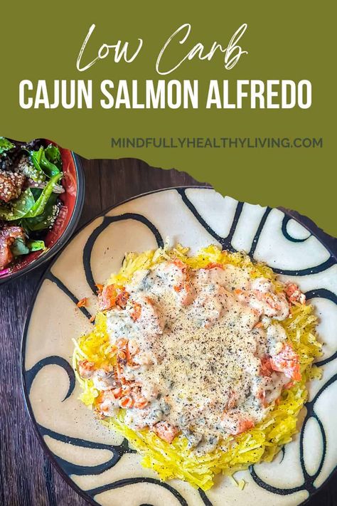 A decorative plate of spaghetti squash topped with salmon chunks and creamy cajun alfredo sauce, seasoned with black pepper. A bowl of salad is visible in the top left corner. At the top is a page looking like it was torn with a green backdrop and text that says, "low carb cajun salmon alfredo mindfullyhealthyliving.com Cajun Salmon Alfredo, Creamy Cajun Salmon, Low Carb Cajun, Salmon Alfredo, Salmon Spaghetti, Cajun Salmon, Alfredo Sauce Recipe Homemade, Pasta Alternative, Healthy Italian