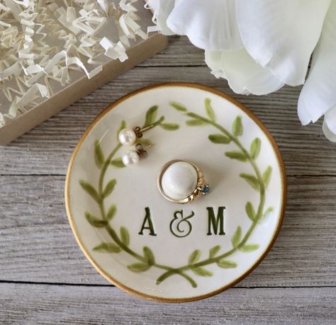 This personalized ring holder or ring dish makes a great engagement gift or wedding gift for the couple.  It features a ring cone to keep her ring secure should she ever take it off.  Handmade and customized with the couples initials and a laurel leaf design. Finished with a sparkly gold edge.  The couple's wedding date can be added under the monogram. This round dish measures approx. 3 1/2" wide and 1 1/2" tall. Before leaving our studio, we gift box this dish so it arrives ready to give. If yo Ring Holders Diy, Ceramic Wedding Gift, Engagement Gifts Diy, Creative Engagement Gifts, Ring Holder Pottery, Diy Ring Dish, Pottery Ring Holder, Diy Engagement Gifts, Personalized Wedding Ring Holder