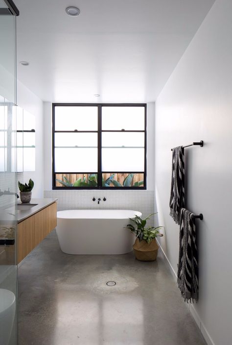 This bathroom uses minimal tiles featuring a burnished concrete floor and only a section of tile behind the bath and vanity splash. Minimalist style black, white and timber bathroom. See all the photos from this home tour on the blog. Burnished Concrete Floor, Concrete Floors Bedroom, Polished Concrete Bathroom, Bathroom Concrete Floor, Burnished Concrete, Style Curator, Matte Black Wall, Wall Basin, Timber Vanity