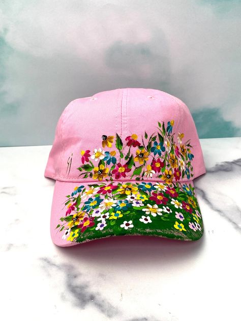 Here is another Ivy Cottage Art Gifts painted pink baseball cap.  It has an adjustable strap in the back to fit most head sizes.  This is a very pretty pink floral cap with the very popular wildflower design.  These colorful flowers  really set off the design against the pink color cap.  This is a great color for summer wear and is painted with enamel paint which can be worn in the rain without coming off.  Notice the little butterfly in the corner as well. Shoes Doodle, Painted Apparel, Painted Caps, Cap Painting, Ivy Cottage, Shirt Painting, Pink Baseball Cap, Wildflower Design, Fabric Painting On Clothes