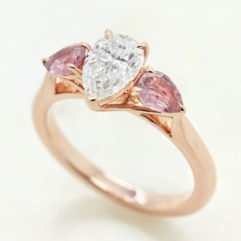 pear diamond rose gold trilogy engagement ring with pink pear sapphire accent stones Diamond Ring With Pink Side Stones, Pear Trilogy Engagement Ring, Sapphire Ring Designs, Custom Sapphire Engagement Ring, Taylor Hart, Pear Diamond Ring, Diamond Dress Ring, Trilogy Engagement Ring, Engagement Ring Designs