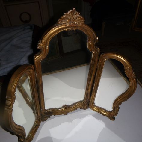 Being offered is this ornate gold toned wooden framed Mirror. Measuring  26 1/2" wide open, 24 1/4" high and  12'closed.. It is very heavy 10+ pounds unpackaged.. It does have some chipping/flaws   thru-out mainly on the sides. The mirror rests on ornate feet and the top is adorned with Acanthus foliage. This is an old used mirror in great vintage condition despite it's age. Thank You for viewing. Antique Standing Mirror, Large Decorative Mirrors, Vintage Decor Pieces, Full Size Mirror In Bedroom, Antic Mirror, 80s Mirror, Antique Vanity Mirror, Antique Room Decor, Triptych Mirror