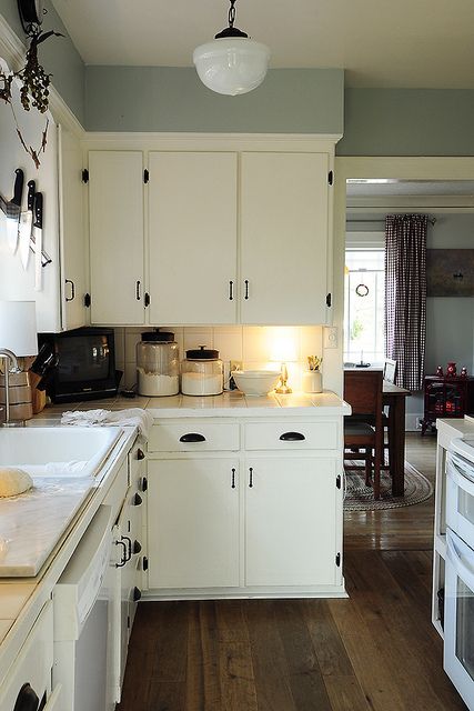 love the drawer pulls, the floors, and the rug under the table, love it all White Kitchen Interior Design, White Kitchen Interior, Eclectic Kitchen Design, Beautiful White Kitchens, Country Kitchen Cabinets, Rustic Kitchen Cabinets, Apartment Decoration, Eclectic Kitchen, Kitchen Cabinets Decor