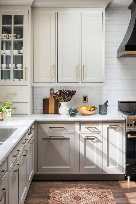 A black French range hood mounted to white subway backsplash tiles over a black French range placed beside gray kitchen cabinets accented with brass pulls and a white quartz countertop. Toilette Design, Walker Zanger, Kitchen New York, Kabinet Dapur, Farmhouse Kitchen Cabinets, Counter Tops, Kitchen Remodel Idea, Farmhouse Kitchen Decor, Traditional Kitchen