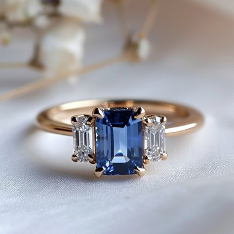 SETTING ONLY: SELECT YOUR STONE → How to build your own ring: STEP 1. Select a stone and add it to your cart STEP 2. Select your setting and add it to your cart. STEP 3. Once your order is confirmed we custom make your ring from scratch. The Atlahua Ring, is an elegant and sophisticated three stone ring featuring a center emerald cut blue Sapphire accented by two emerald cut lab diamonds. Crafted with precision, the custom sourced emerald cut sapphire takes center stage and is artfully set on a Blue Ring Engagement, Diamond With Sapphire Side Stones, Sapphire Emerald Cut Engagement Ring, Ringo Star, Wide Gold Ring, Sapphire Side Stones, Blue Wedding Rings, Blue Sapphire Diamond Ring, Ethical Engagement Ring