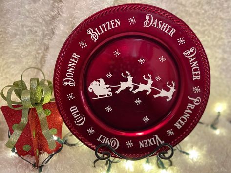 Santa's sleigh is flying through the sky in the middle of this beautiful 13" red charger plate with the all reindeer names along the outer edge. This is sure to be a hit with anyone of all ages! Would make a great addition to any Christmas décor. Would make a great gift too! Not food safe (for decorative use only). Plate stand is not included. Thanks for looking! Any order $35 or more gets Free Shipping! Charger Plates Christmas, Charger Plates Decor, Red Charger, Platter Plates, Sleigh With Reindeer, Reindeer Names, Santa's Reindeer, Merry Bright Christmas, Santa's Sleigh