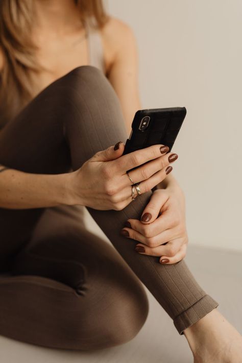 Young woman with brown nails in yoga clothes holding mobile phone Woman Yoga, Brown Leggings, Yoga At Home, Brown Nails, Yoga Studio, Free Design Resources, Yoga Women, Young Woman, Yoga Clothes