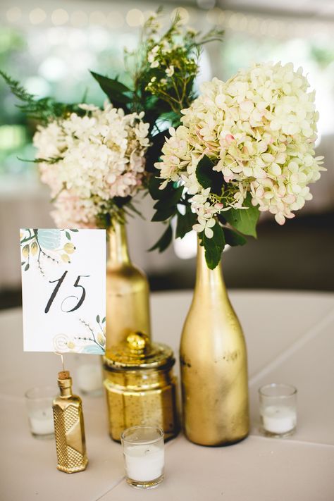 Painted Wine Bottle Centerpieces, Gold Bottle Centerpiece, Gold Painted Bottles Centerpiece Ideas, Gold Wine Bottle Centerpiece, Gold Spray Paint Diy, Spray Painted Wine Bottle Centerpieces, Gold Vase Center Pieces, Spray Painted Wine Bottles, Wine Bottle Wedding Centerpieces