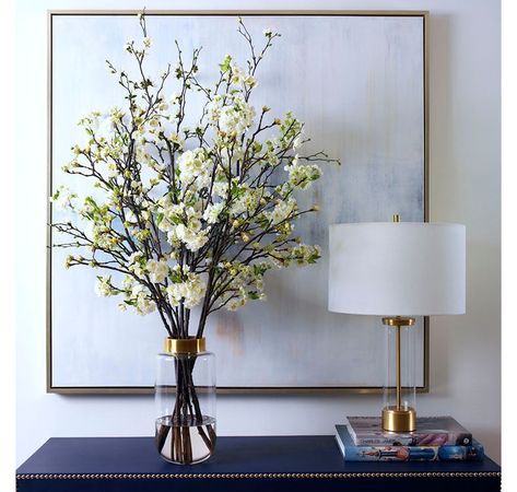 A symbolic flower of spring, the cherry blossom's life is very short, reminding us to fully embrace the seasons as they come. Our faux blossoms arranged in a glass vase topped off with a gold band capture the fleeting nature of spring yet allow you to enjoy the beauty all year long.  Overall Dimensions: 36" diameter x 48" tall Composed of: cherry and quince blossoms and budding branches; textured glass vase with gold accents Modern Arrangements, Dining Room Console, Container Dimensions, Faux Floral Arrangement, Faux Flower Arrangements, Artificial Flowers And Plants, Pink Plastic, Entry Table, Faux Florals