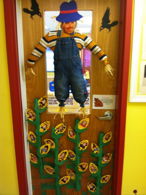 Its our classroom door.  Very easy. Scarecrow stuffed with newspaper and hay sticking out. Cornstalks are covered papertowel rolls.  Corn cut out of construction paper with fingerprints as corn then kids pictures attached.  Blackbirds off google and cut out.  My picture as scarecrow face.  Everyone loves it and very easy Corn Door Decoration, Scarecrow Door Classroom, Halloween Classroom Door Contest, Farm Vbs Decorations, Corn Activities, Farm Vbs, Preschool Door Decorations, Corn Theme, Cats Room