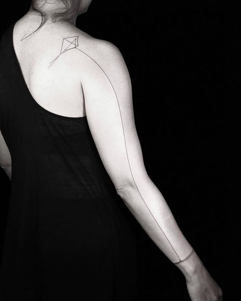 Kite Shoulder Tattoo. A kite tattoo with an elegant tail line that extends down the arm. Click through for 50 shoulder tattoo ideas. #shouldertattoos #tattooideas #tattoos IG: @bangbangnyc Seam Line Tattoo, Line Tattoo Meaning, Tattoo Duo, Kite Tattoo, Line Tattoo Arm, Full Hand Tattoo, Butterfly Tattoo On Shoulder, Abstract Tattoo Designs, Stylish Tattoo