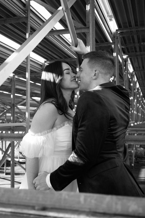 Couple kiss under bleachers High School Bleachers Aesthetic, Highschool Couple Photoshoot, High School Sweethearts Wedding, High School Sweethearts Aesthetic, High School Sweethearts Photoshoot, High School Sweetheart Engagement Photos, Engagement Photos High School Sweetheart, Record Store Engagement Photos, High School Sweetheart Photoshoot