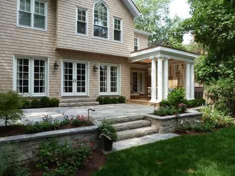 Raised Back Patio, Raised Stone Patio Ideas, Stone Patio With Retaining Wall, Backyard Raised Patio Designs, Back Patio With Steps Down From House, Back Porch Stairs, Raised Concrete Patio Ideas, Patio Retaining Wall Ideas, Raised Patio Ideas With Steps