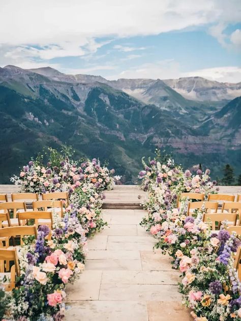 scenic outdoor wedding ceremony venue with mountain peaks in the distance and aisle lined with lush florals Wedding Flowers Down The Aisle, Wedding Alter Outdoors, Spring Wedding Isles Decoration, Wedding Table Centerpiece Ideas, Garden Wedding Altar, Sunset Wedding Ceremony, Scenic Wedding Venues, Wedding Flower Trends, Scenic Wedding