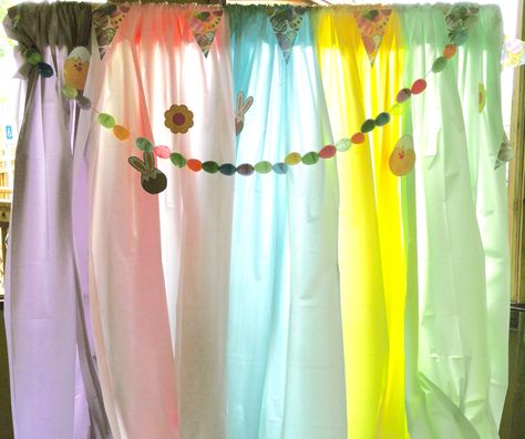 Easter photo backdrop made with pastel plastic table cloths hung on DIY PVC background stand. Strung plastic Easter eggs on curling ribbon and draped in front as egg garland. Added Easter cutouts for more decoration. Easter Diy Backdrops, Easter Backdrop, Easter Photo Backdrop Ideas, Easter Basket Alternatives, Easter Photo Booth, Easter Photo Backdrop, Pipe And Drape Backdrop, Easter Backdrops, Diy Photo Backdrop