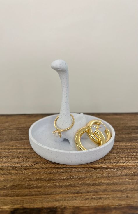 Transform your jewelry display into a prehistoric delight with our Dinosaur Jewelry Holder - a whimsical and adorable addition to your collection. This Cute Dino Ring Stand is designed for both style and functionality, serving as a charming Dino Ring Organizer for your favorite rings. 🎁 Product Details: Material: High-Quality Marble PLA plastic Dimensions: Length 3.5 inches x Width 3.5 inches x Height 3.4 inches Color: Elegant Marble White 🌎 Conscious Crafting: We take pride in our environmentally conscious approach. Our items are 3D-printed with eco-friendly materials. 📸 Please Note: Accessories in Photos Not Included The product images may showcase accessories or additional items for decorative purposes only. Please be aware that the Ring/Earrings featured in the photos are not includ Clay Hand Jewelry Holder, Jewelry Holder With Clay With A Cap, Jewlrey Holders Ceramic Diy, Ceramic Ring Holder Pottery, Ceramic Ring Holders, Air Clay Jewelry Holder, Pottery Earring Holder, Jewelry Organizer Diy Clay, Ring Dish Pottery