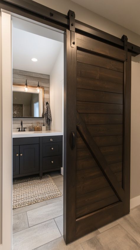 A dark wooden barn door opens to a modern farmhouse bathroom featuring a white sink and black vanity. Farmhouse Half Bathroom Ideas, Farmhouse Half Bathroom, Half Bathroom Decor Ideas, Half Bathroom Decor, Wooden Barn Doors, Wainscoting Bathroom, Earthy Living Room, Wooden Barn, Farmhouse Aesthetic