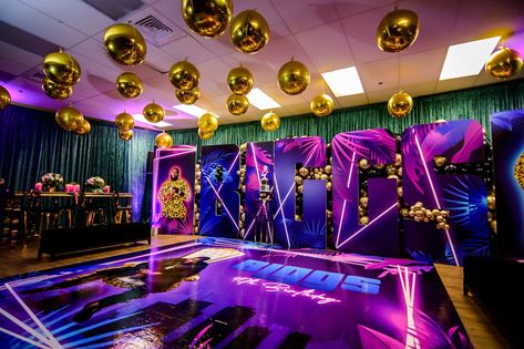 This Miami Vice themed milestone birthday had guests dancing the night away in this over-the-top nightclub atmosphere. S. Dulcio Florals & Design brought the room to life adding a customized dance floor, pink candles, metallic golden disco balls, and golden chairs all accenting the vibrant pink and blue strobe lights. Guests in attendance were welcomed with a champagne wall, followed by signature cocktails from the bar, food, and a three-tiered Miami Vice decorated cake. Birthday In Miami, Miami Vice Party, Miami Vice Theme, Golden Chair, Unique Party Themes, Champagne Wall, Gala Ideas, Bar Food, Signature Cocktails