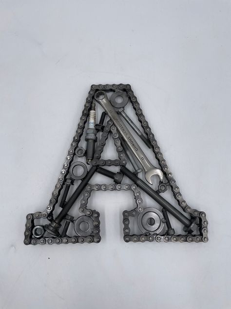 Car Parts Initial Letter A, Monogram Letter Wall Art, Automotive Wall Decor Here you can order a custom built letter 'A' created with automotive parts. Timing chain outlines the letter, with a great variety of car parts used in the design. This is a handmade - built to order item, so if you would like any particular brand of car parts included in the build, please let me know! You can order your letter to be 8, 11 or 16 inches in height. The letters can be built at any size, so if you would pref Diy Car Parts Decor Ideas, Car Part Art Automotive Decor, Horseshoe Welding Projects Beginner, Car Themed Decor, Easy Welding Projects To Sell, Welding Projects Decor, Things To Weld, Scrap Metal Art Car Parts, Diy Metal Wall Art