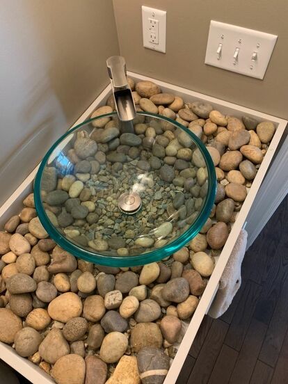 This is our natural river rock counter for our rustic , nature like half bath off our family room. We wanted something “artist” and different because you can see the bathroom from the family and kitchen area as we have a very open house plan. We painted the room a warm Med brown . The cabinet is beige gray and we have a green wreath and two Paintings with green ferns in them. We made a wood tray 3 “ deep and painted it the exact color of the cabinet. We then installed the vessel sink… River Rock Bathroom, Rock Bathroom, Diy River Rock, Modern Pedestal Sink, Accent Wall Stencil, Open House Plans, Washbasin Design, Turkish Tiles, Bathroom Counters