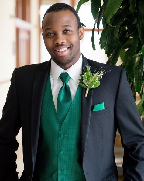 Love the greenery in the boutonnière that plays off of the green vest and sharp black suit. For more ideas for boutonnières, click the link to be taken to our Pinterest Board full of inspiration photos. Black Tuxedo With Green Tie, Black And Green Tuxedo, Black Tuxedo With Emerald Green Tie, Black And Emerald Tuxedo, Black Tuxedo With Green Accents, Black Suit Green Vest, Grad Suits, Green Tuxedo, Tuxedo Vest