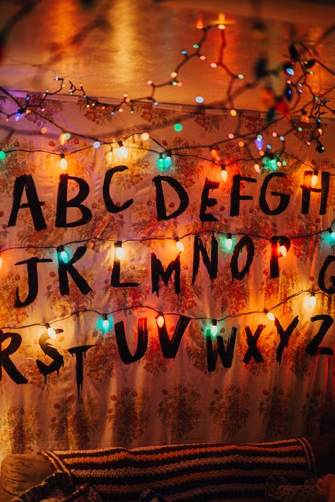 Stranger Things party decorations / Byers living room. “Wallpaper” diy using a floral sheet and iron on letters printed from the computer onto dark fabric transfer paper. Christmas lights plugged into a light controller found on Amazon that allows lights to flicker and flash with various settings you can set yourself. Stranger Things Christmas Wallpaper, Stranger Things Christmas Lights, Christmas Lights Drawing, Stranger Things Wall, Stranger Things Lights, Stranger Things Tattoo, Stranger Things Christmas, Christmas Lights Wallpaper, Stranger Things Halloween