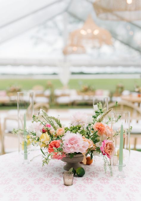 an outdoor wedding reception with a garden party theme. there is a clear tent with rattan hanging pendant lights and rattan furniture. the table linen is pink and white patterned. the beautiful florals on the table are pink, yellow, and orange. Stradley Davidson, White Wedding Reception, Pink And White Wedding, White Weddings Reception, Clear Tent, Pink And White Weddings, Floral Business, Floral Tablecloth, Pink Floral Pattern