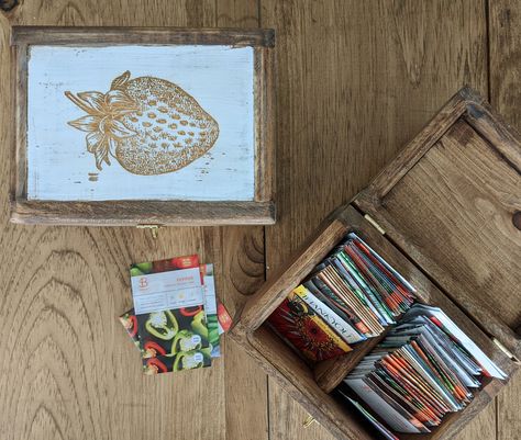 "This rustic wooden box was designed to store and organize seed packets. It's perfect for getting an unruly collection under control or as a gift for a budding gardener. PLEASE NOTE: Seeds are NOT included with this item. This listing is only for the storage box. We built these boxes using a mixture of northern white pine and reclaimed wood. The wood is sanded and finished in English Chestnut. The top of the lid is painted in a distressed white finish and engraved with an image of a strawberry. Cottage Cozy, Seed Vault, Seed Storage, Rustic Wooden Box, Seed Box, Strawberry Seed, Lid Organizer, White Pine, Seed Packets