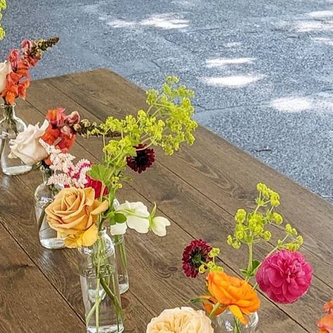 Jessica Anselmi | Artist on Instagram: "Sometimes bud vases are the perfect centerpiece choice- especially on farmhouse style tables like these from @gallatineventrental 🙌✨ Styling this look requires way more than just dropping some flowers into vases and calling it good. Color combination, varied heights, textures, movement, size of blooms, and vase placement all need to be well thought out to create a beautiful, cohesive table. Who knew?!?! 🤣🤓 For yesterday's garden wedding- literally at the Bride's parent's backyard garden with tons of sentimental value + special memories- lush garden roses and peonies popped with local snapdragon, ranunculus, ladies mantle, sweet peas, chamomile daisy, and a few special dahlias tucked into the bride's bouquet 🧡🧡🧡 @rathvinden @calliopeflowersmt @k Ladies Mantle, Roses And Peonies, Lady's Mantle, Bride's Bouquet, Farmhouse Style Table, Sweet Peas, Garden Roses, Lush Garden, Bride Bouquets